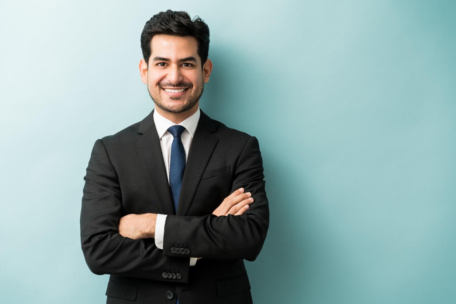 smiling-young-male-professional-standing-with-arms-crossed-while-making-eye-contact-against-isolated-background (1)
